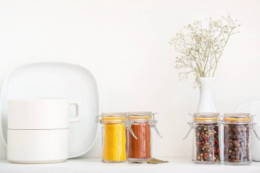 Mutfaktaki raflarda farklı baharatlar ve yemekler olan kavanozlar.