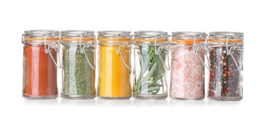 Beyaz arkaplanda farklı baharatlar bulunan kavanozlar