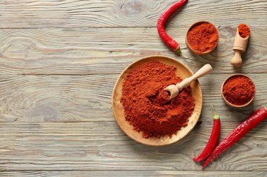 Ahşap zemin üzerinde kırmızı biber tozu olan tabak ve kaseler.