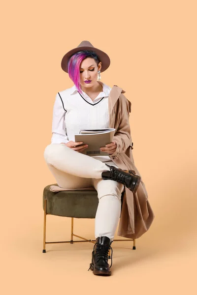Portrait of extravagant stylish woman with magazines on color background