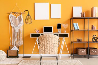 Ofiste renkli duvarın yanında dizüstü bilgisayarı olan şık bir iş yeri