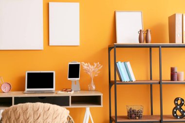 Ofiste renkli duvarın yanında dizüstü bilgisayarı olan şık bir iş yeri