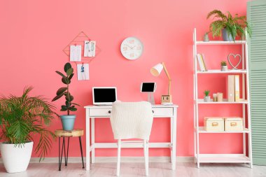 Ofiste renkli duvarın yanında dizüstü bilgisayarı olan şık bir iş yeri