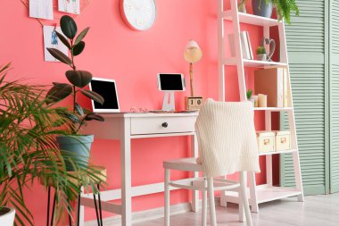 Ofiste renkli duvarın yanında dizüstü bilgisayarı olan şık bir iş yeri