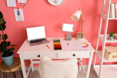 Ofiste renkli duvarın yanında dizüstü bilgisayarı olan şık bir iş yeri