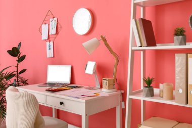 Ofiste renkli duvarın yanında dizüstü bilgisayarı olan şık bir iş yeri