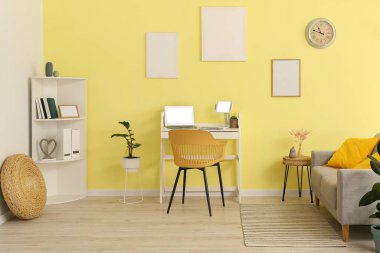 Ofiste renkli duvarın yanında dizüstü bilgisayarı olan şık bir iş yeri