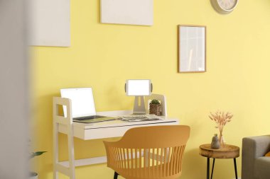 Ofiste renkli duvarın yanında dizüstü bilgisayarı olan şık bir iş yeri