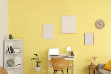 Ofiste renkli duvarın yanında dizüstü bilgisayarı olan şık bir iş yeri