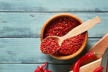 Ahşap arka planda kırmızı biberli kase ve kaşık.