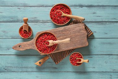 Ahşap arka planda kırmızı biberli kâseler ve kepçeler.