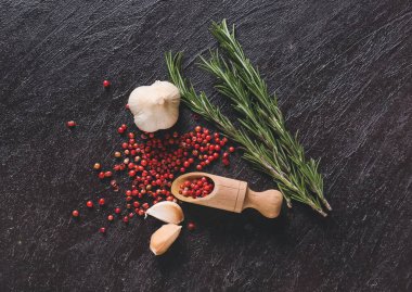 Kırmızı biberli kepçe, koyu arkaplanda sarımsak ve biberiye.