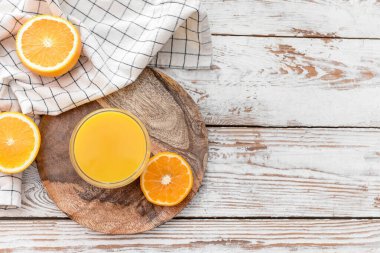 Taze portakallar ve hafif ahşap zemin üzerinde bir bardak meyve suyu.