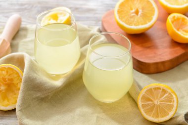 Taze limonlar ve arka planda bir bardak meyve suyu.