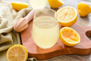 Taze limonlar ve tahta arka planda bir bardak meyve suyu.