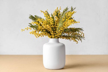 Masada güzel mimoza çiçekleri olan vazo.