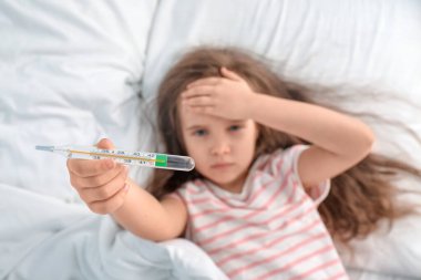Yatağında termometresi olan hasta küçük bir kız.