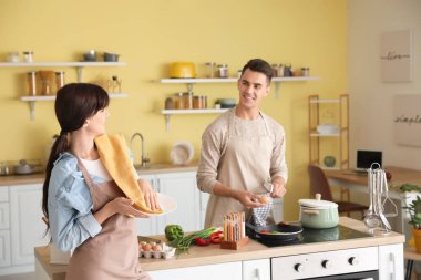 Mutlu genç çift bulaşıkları yıkıyor ve mutfakta yemek pişiriyor.