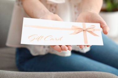 Young woman with gift card at home, closeup clipart