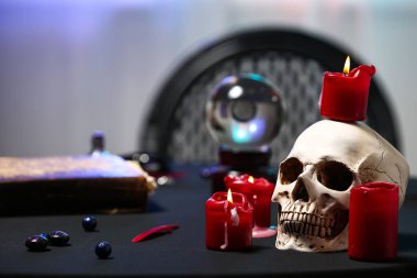 Falcı masasında insan kafatası ve mumlar.