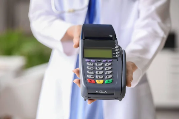 Doctor with payment terminal in clinic, closeup