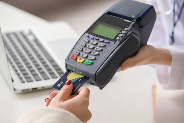 Patient paying for consultation in clinic via terminal, closeup