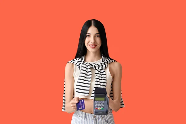 Young woman with payment terminal and credit card on color background