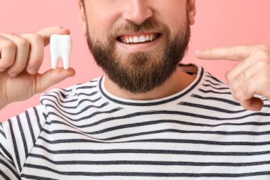 Renkli arka planda plastik dişli genç adam, yakın plan