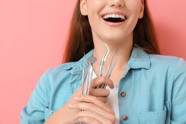 Renkli arka planda diş aletleri olan güzel bir genç kadın, yakın plan.