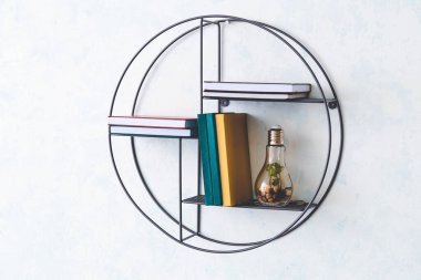 Rafta kitaplar ve lamba asılı.