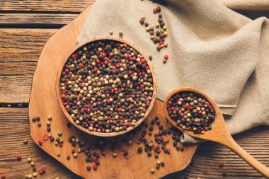 Ahşap arka planda karışık biberli kase ve kaşık.