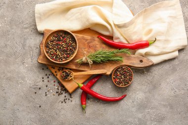 Karışık biberli kompozisyon, kırmızı biber ve gri arka planda biberiye.