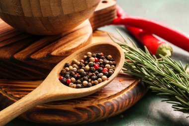 Karışık biberli kaşık, kırmızı biber ve biberiye arka planda, yakın plan.