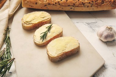 Açık arkaplanda taze ekmek, tereyağı ve biberiye olan tahta, yakın plan