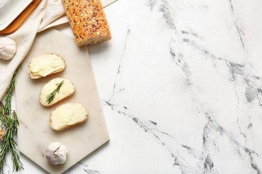 Açık arkaplanda taze ekmek, tereyağı ve biberiye bulunan tahta