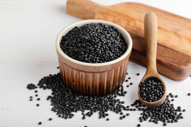 Arka planda siyah mercimek ve kase