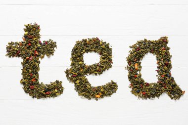 Kelime TEA beyaz ahşap arka planda kuru yeşil yapraklardan yapılır