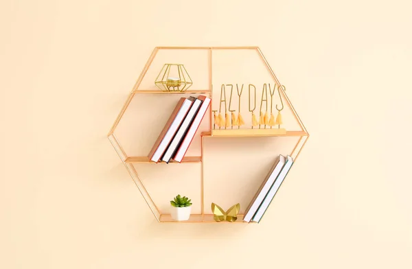 Shelf with books and decor hanging on color wall