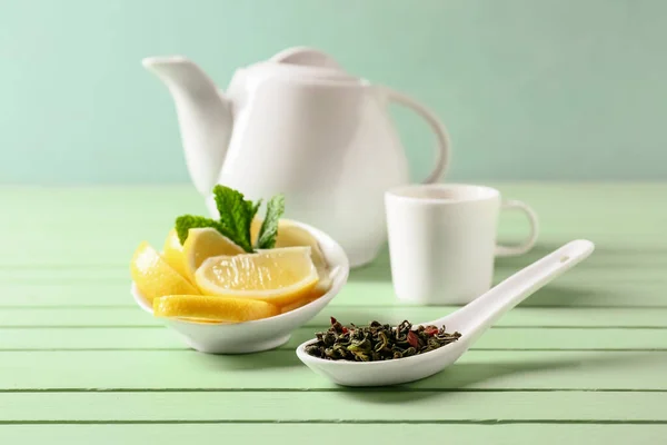 Composition with dry green tea and lemon on color wooden background