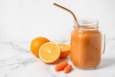 Mason kavanozu dolusu sağlıklı meyve püresi ve hafif arka planda malzemeler.