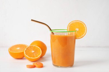 Bir bardak sağlıklı meyve suyu ve beyaz ahşap arka planda malzemeler.