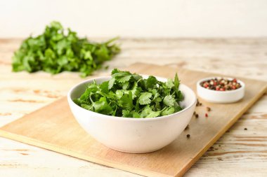 Taze kişniş ve hafif ahşap arka planda biber dolu kaseler.