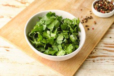 Taze kişniş ve hafif ahşap arka planda biber dolu kaseler.