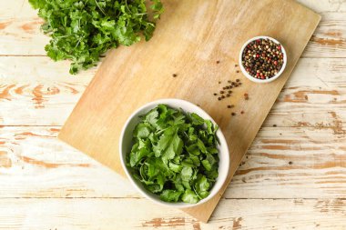 Taze kişniş ve hafif ahşap arka planda biber dolu kaseler.