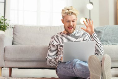 Evde dizüstü bilgisayarı olan genç bir adam.