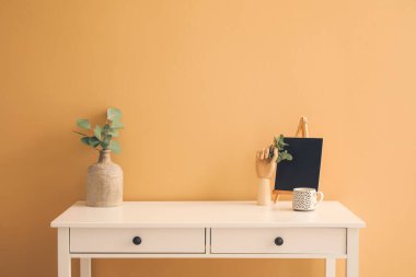 Odanın duvarının yanındaki masada ahşap bir el ve şık bir dekor.