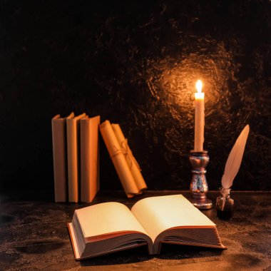 Tüylü eski kitaplar, parşömenler ve yanan mumlar karanlık arka planda.
