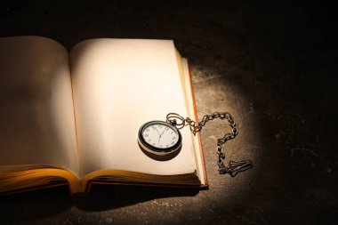Koyu arkaplanda saat olan eski kitabı aç