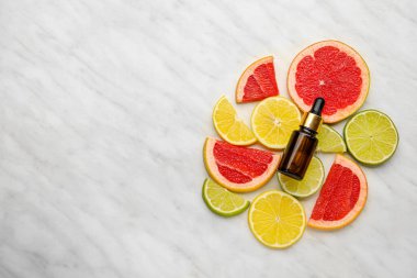 C vitamini ve arkaplanda turunçgil dilimleri olan bir şişe.