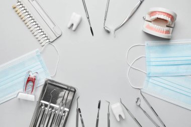 Açık arkaplanda dişçi araçları, çene modeli ve diş renk örneklerinden oluşan çerçeve